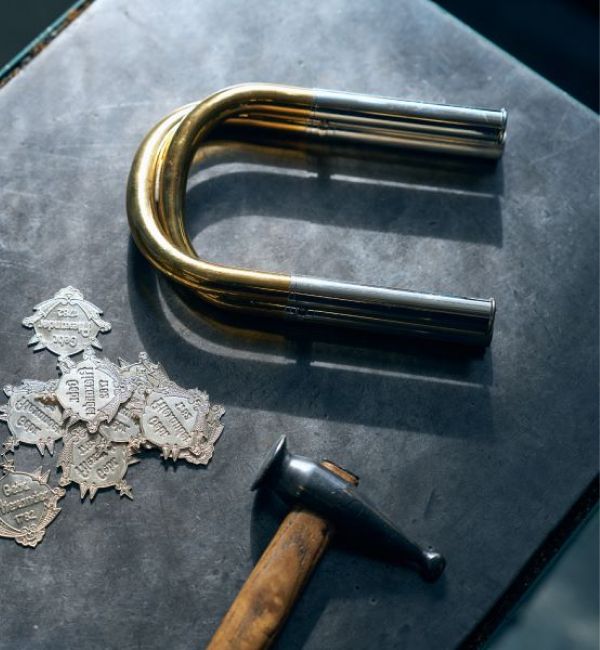 Ein Foto von einem Hammer, Metallblatten und gebogenem Rohr.
