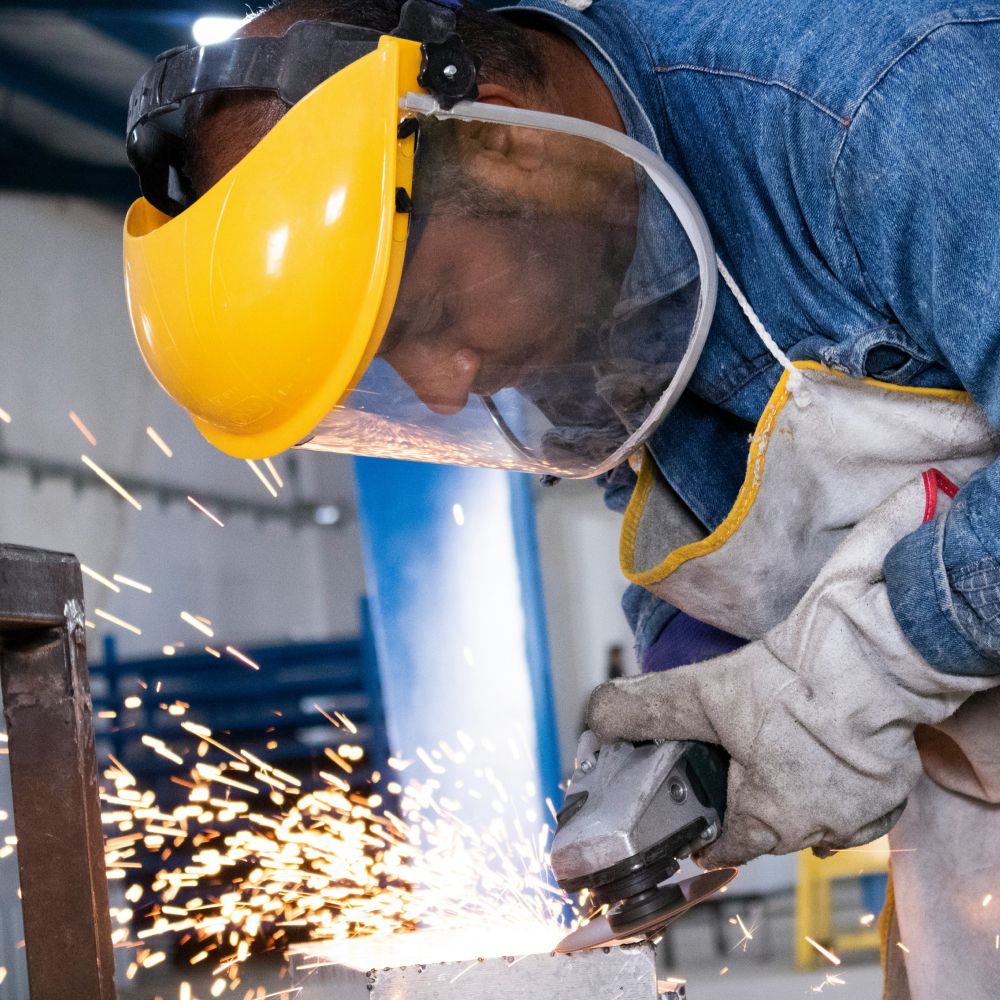 Dieses Bild zeigt einen Arbeiter der einen Winkelschleifer benutzt und verdeutlicht das Thema Industriestrompreis 2025