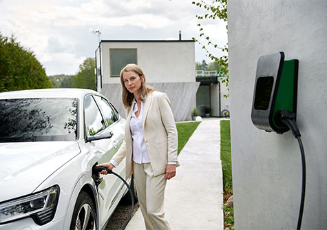 Vattenfall eMobility zuhause laden Frau lädt E-Auto vor Haus