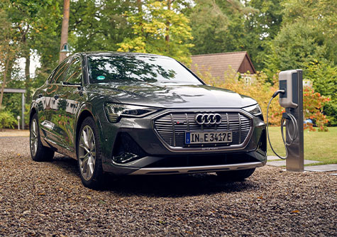 Grauer Audi steht neben einer Ladestation