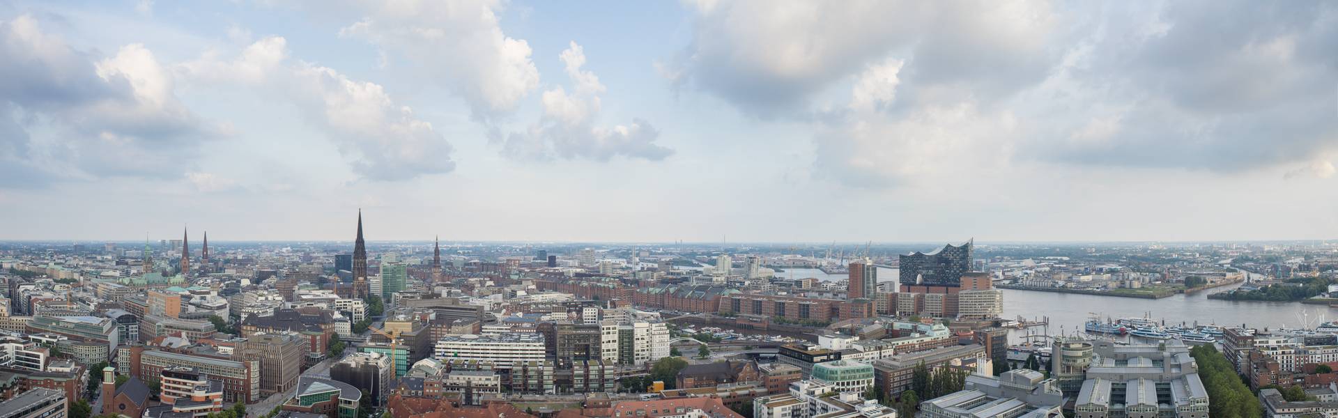 Blick über die Skyline von Hamburg mit der Elbphilharmonie und dem Hafen im Vordergrund.