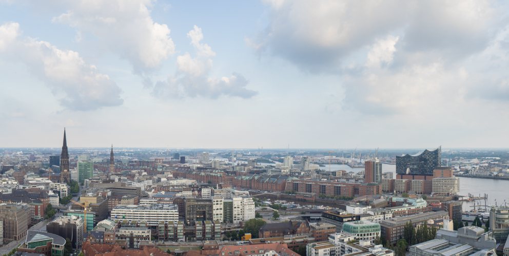 Blick über die Skyline von Hamburg mit der Elbphilharmonie und dem Hafen im Vordergrund.