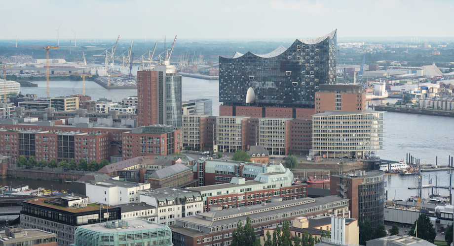 Blick über die Skyline von Hamburg mit der Elbphilharmonie im Vordergrund und dem Hafen dahinter.