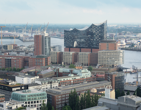 Blick über die Skyline von Hamburg mit der Elbphilharmonie im Vordergrund und dem Hafen dahinter.