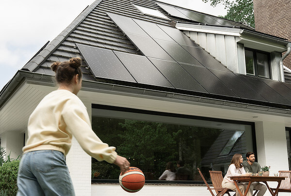 Familie vor Haus mit Solarzellen auf dem Dach