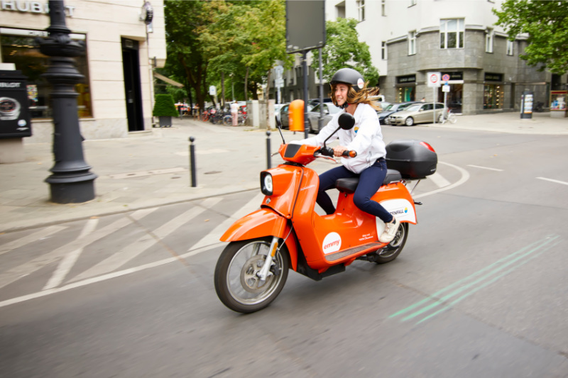 Junge Frau fährt mit dem E-Scooter durch die Stadt