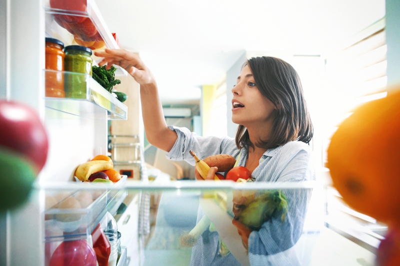 Frau macht Ordnung im Kühlschrank
