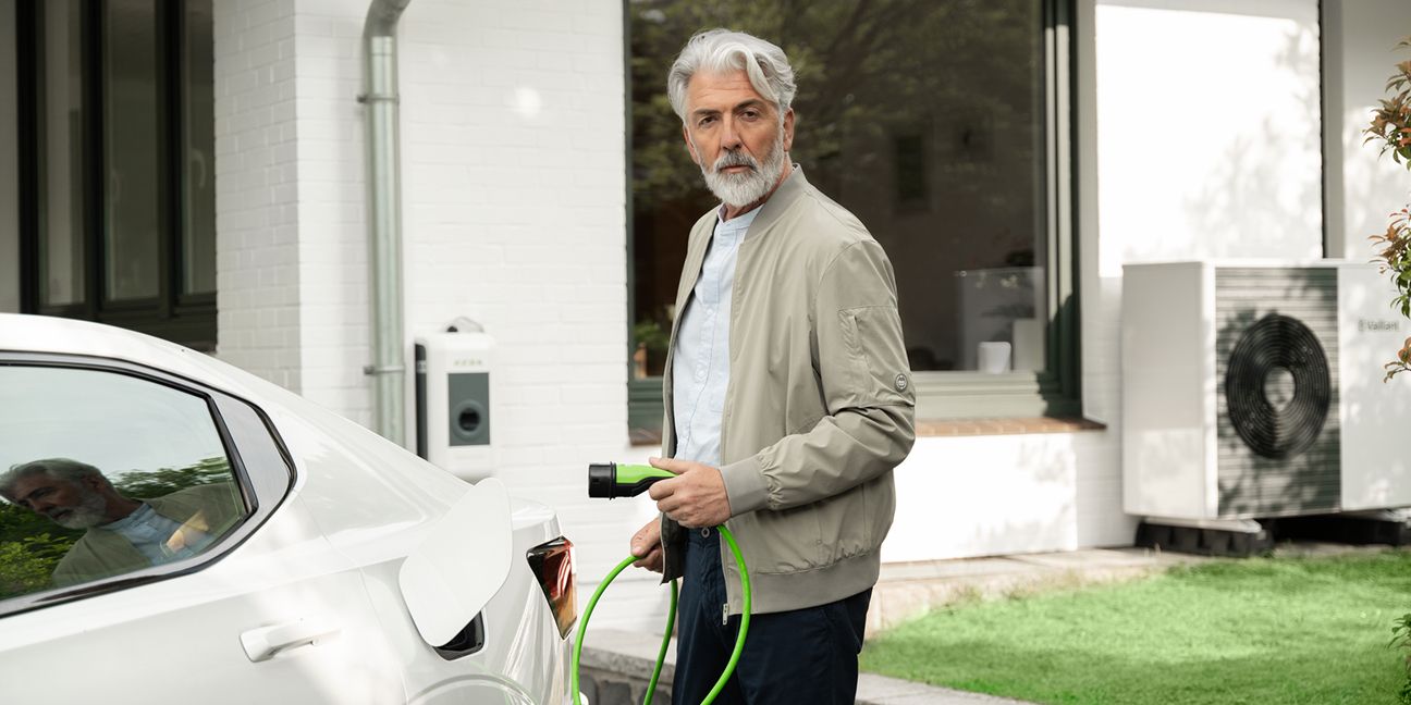 Dieses Bild zeigt einen Mann der ein Elektroauto lädt und verdeutlicht das Thema Dienstwagenbesteuerung