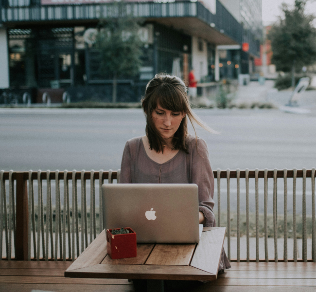 Remote Work: Woman on a macbook, a street behind her