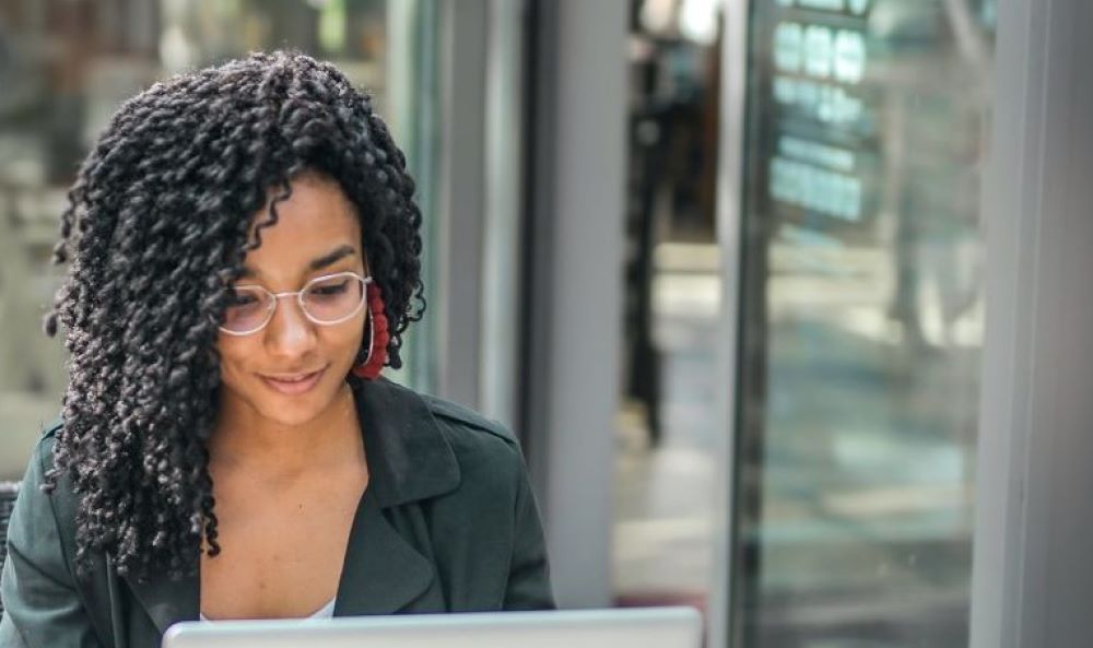 Generation Z - Fachkräfte gewinnen - eine Frau mit lockigen Haaren sitzt an einem Notebook im Café