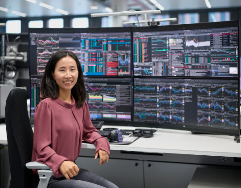 Frau vor mehreren Bildschirmen