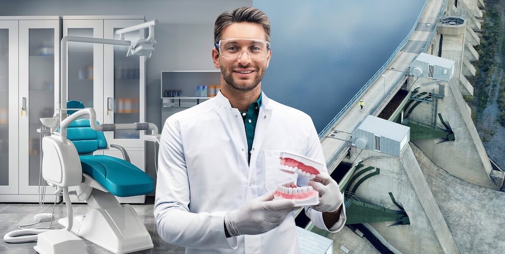 Ein Zahnarzt steht mit einem Gebiss in der Hand in der Praxis.