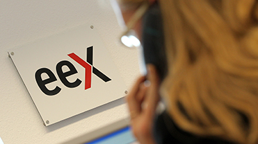 EEX Logo, Schulterblick über telefonierende Frau