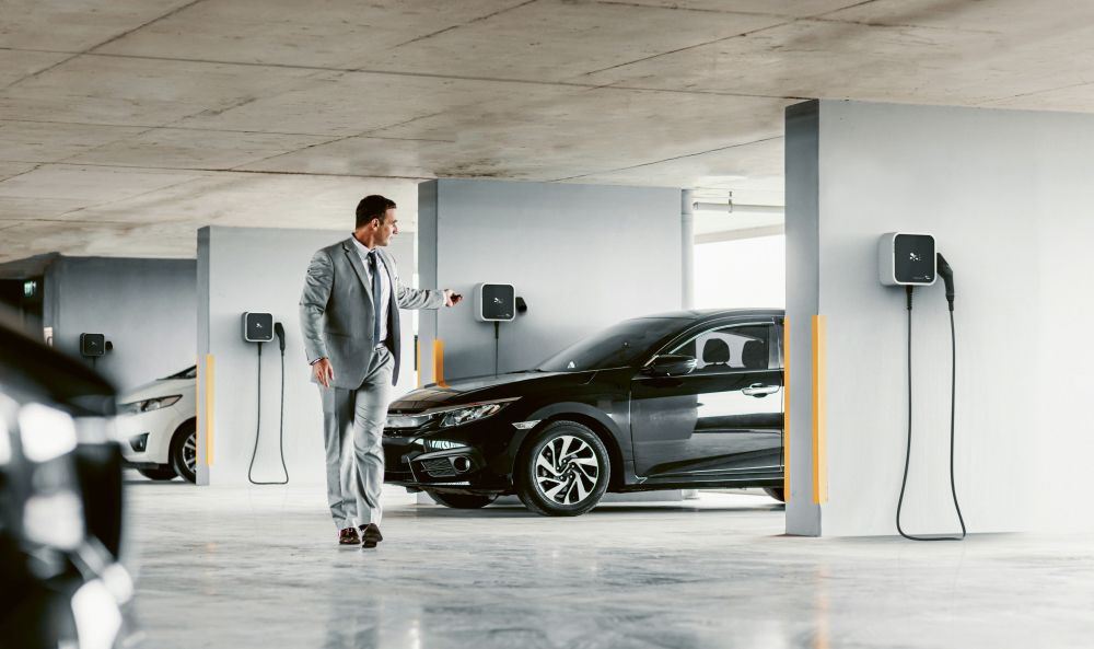 Wallbox Förderungen - Mann in Parkgarage vor Wallbox mit Auto