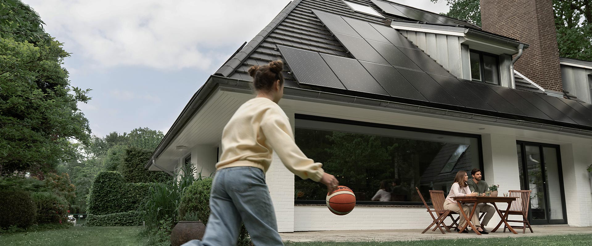 Mädchen spielt vor Haus mit Solaranlage