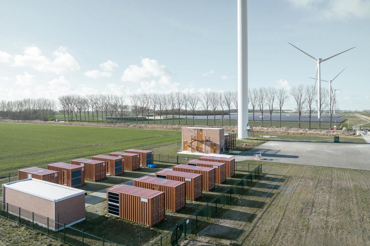 Ein Energiepark in den Niederladen mit Windturbinen und 12 Hochseecontainern mit Großbatterien zur Energiespeicherung.