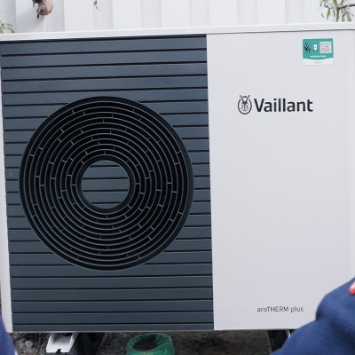 Wärmepumpe vor einem Haus mit verschneitem Dach