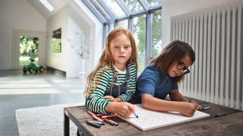 Kinder malen an einem Tisch im Wohnzimmer