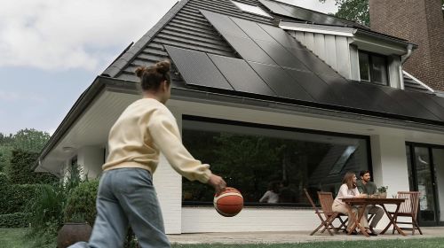 Mädchen spielt mit einem Ball vor einem Einfamilienhaus