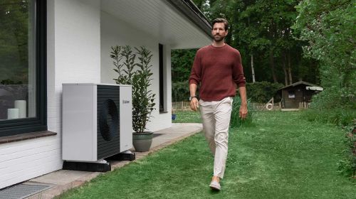 Mann im Garten neben einer Wärmepumpe