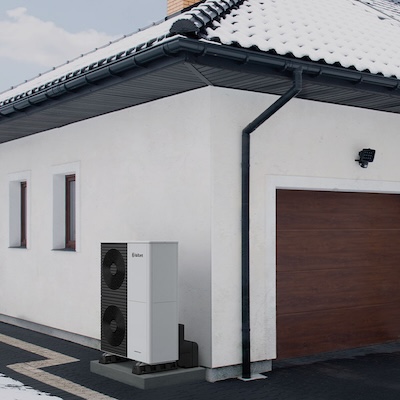 Wärmepumpe vor einem Haus mit verschneitem Dach