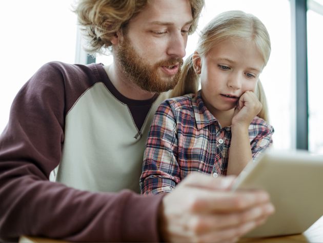 Ein Mann und ein Mädchen schauen auf ein Tablet