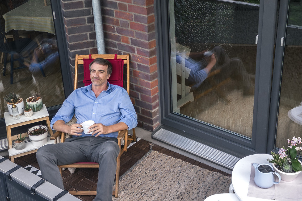Ein Mann sitz auf einem Balkon und schaut in die Ferne