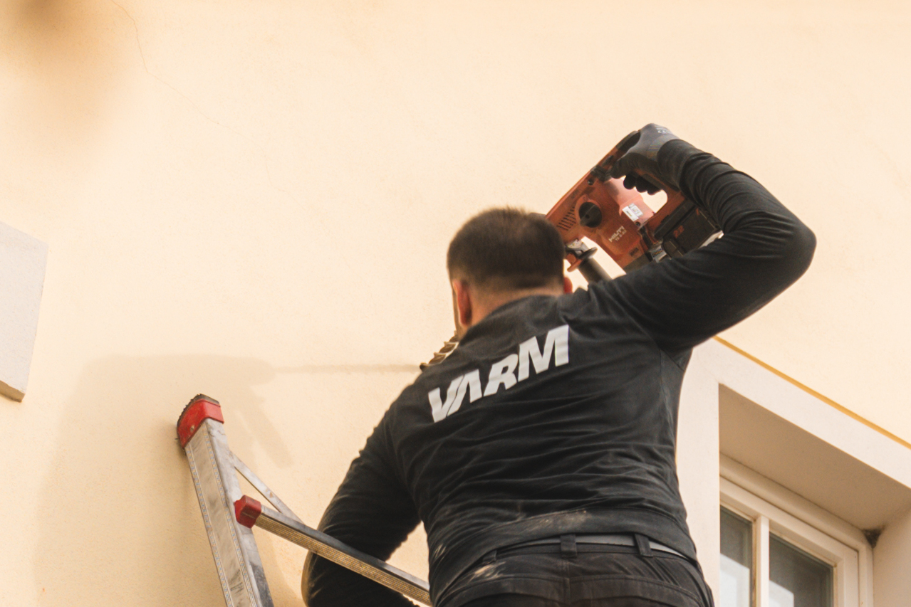 Ein Mitarbeiter von Varm bohrt in eine Hauswand