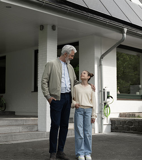 Opa und Enkeltochter stehen vor einem Haus