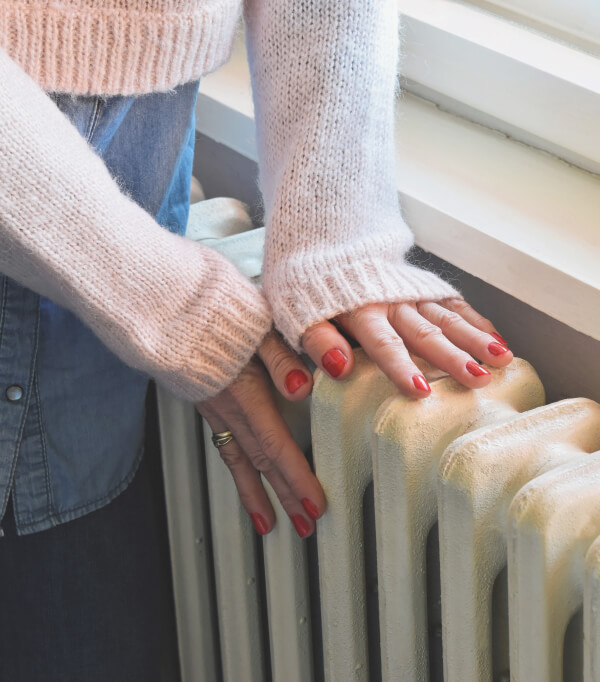 Frau prüft, ob der Heizkörper warm ist