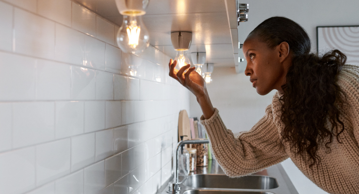 Frau tauscht Leuchtmittel in Küche aus