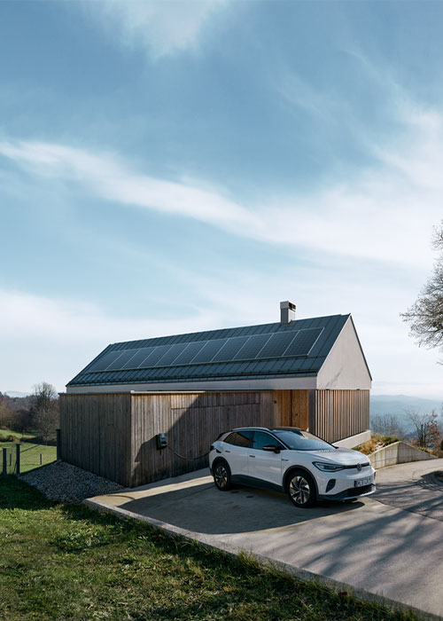 Haus mit Solaranlage auf dem Dach, davor lädt ein E-Auto an der Wallbox