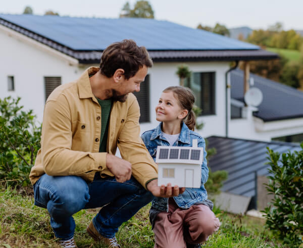 Vater und Tochter vor einem Haus mit PV-Anlage