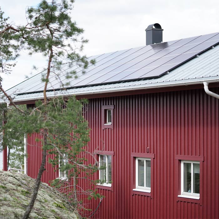 Rotes Holzhaus mit Solaranlage auf dem Dach