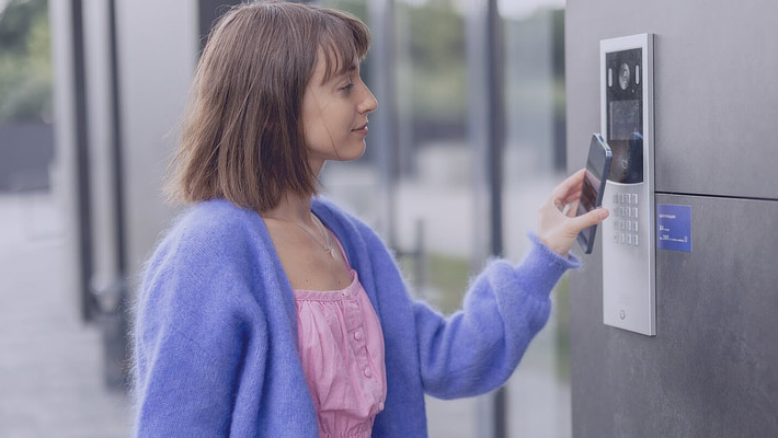 Frau öffnet Haustür per Smartphone