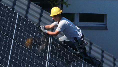 Mann bringt Solarpaneele auf Dach an