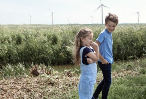 Kleine Kinder auf dem Feld, im Hintergrund – Windräder