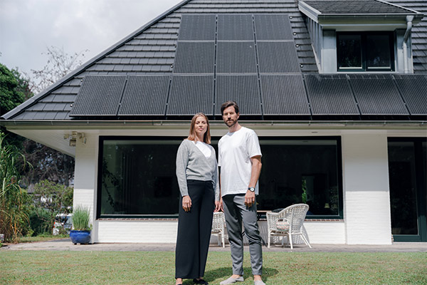 Mann und Frau vor einem Haus mit Solaranlage auf dem Dach