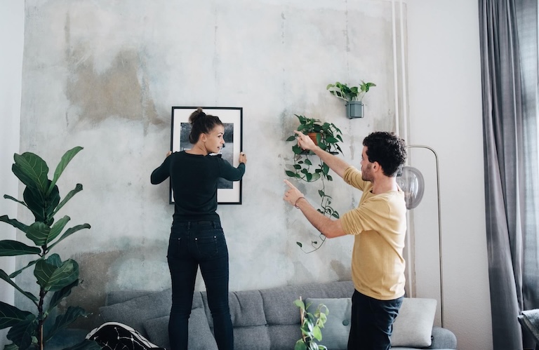 Frau und Mann bringen ein Bild an  die Wand