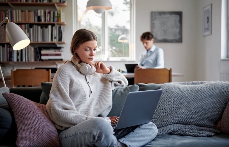 Frau sitzt vor dem Laptop auf dem Sofa