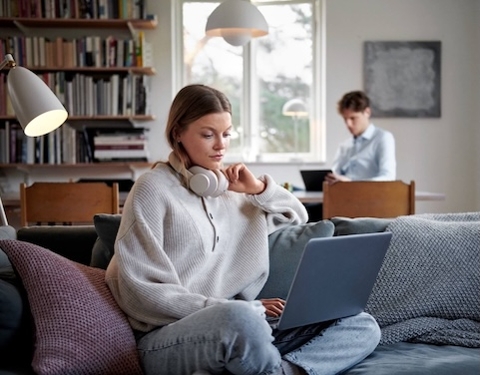 Frau sitzt vor dem Laptop auf dem Sofa