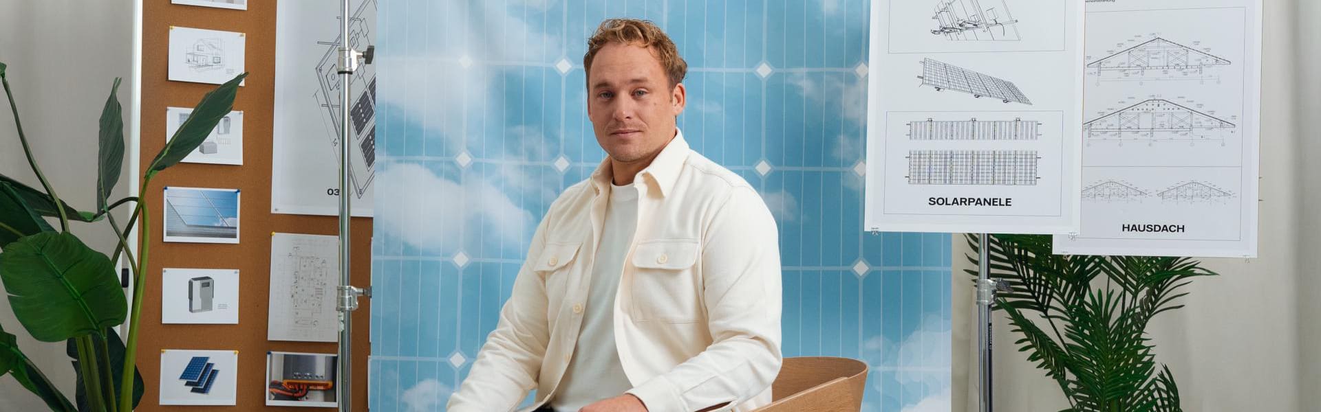 Mann sitzt im Fotostudio vor einer Wand mit Zeichnungen.