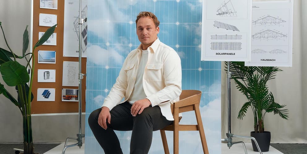 Mann sitzt im Fotostudio vor einer Wand mit Zeichnungen.