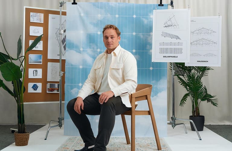 Mann sitzt im Fotostudio vor einer Wand mit Zeichnungen.