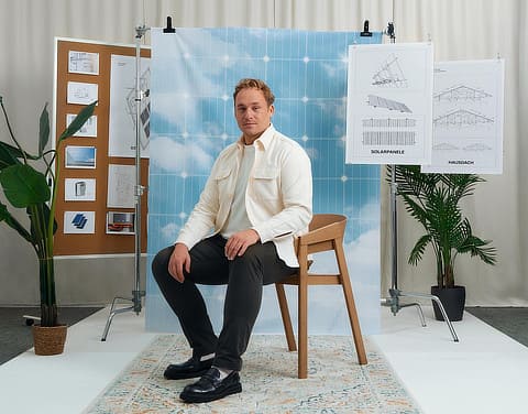 Mann sitzt im Fotostudio vor einer Wand mit Zeichnungen.