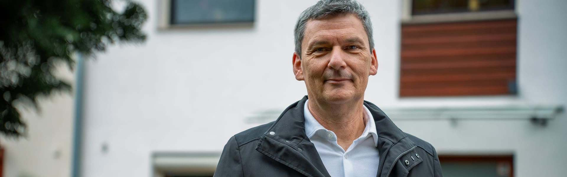 Vattenfall PV-Kunde steht von seinem Haus und schaut in die Kamera