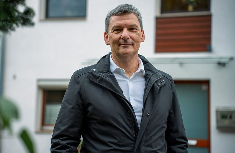 Vattenfall PV-Kunde steht von seinem Haus und schaut in die Kamera