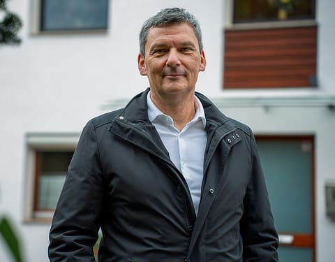 Vattenfall PV-Kunde steht von seinem Haus und schaut in die Kamera