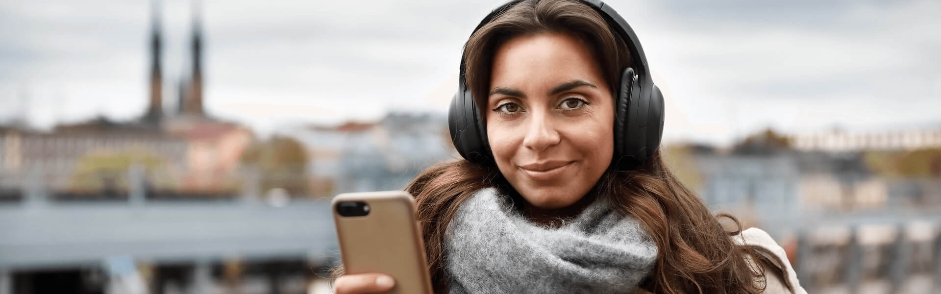 Frau steht draußen auf einer Brücke und schaut aufs Handy.