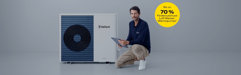 Mann sitzt vor einer Wärmepumpe